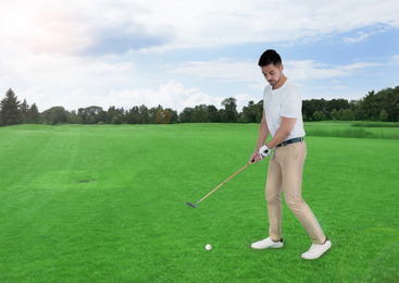 Image of Young man playing golf on course with green grass. Space for design