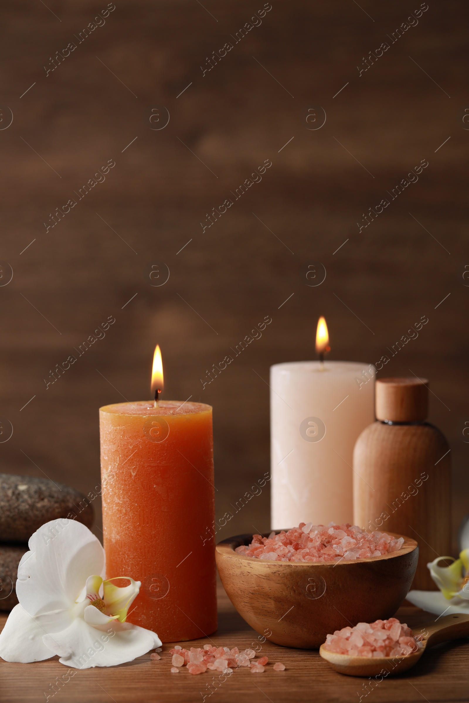 Photo of Beautiful spa composition with sea salt, burning candles and flowers on wooden table