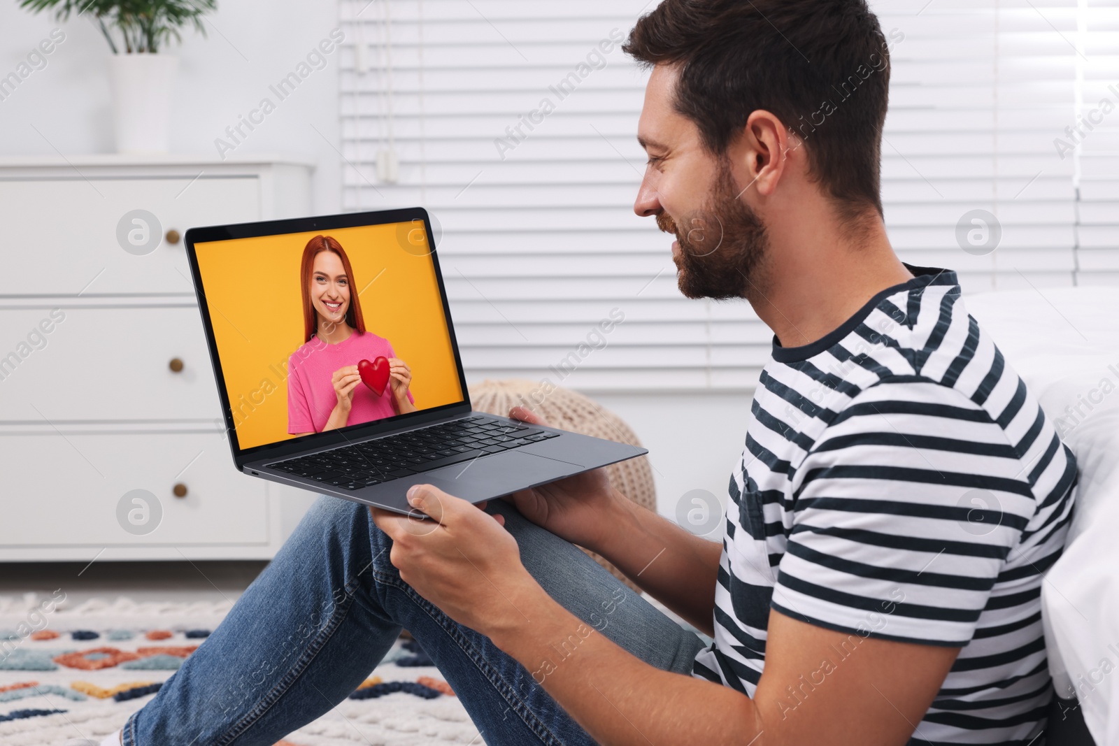 Image of Long distance love. Man having video chat with his girlfriend via laptop at home