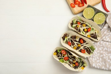 Delicious tacos with fried meat, vegetables and cheese on white wooden table, flat lay. Space for text