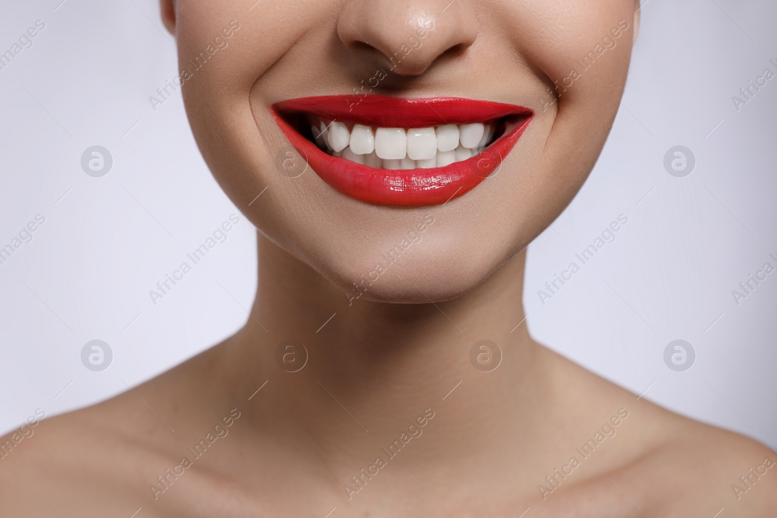 Photo of Young woman with beautiful lips makeup on light background, closeup