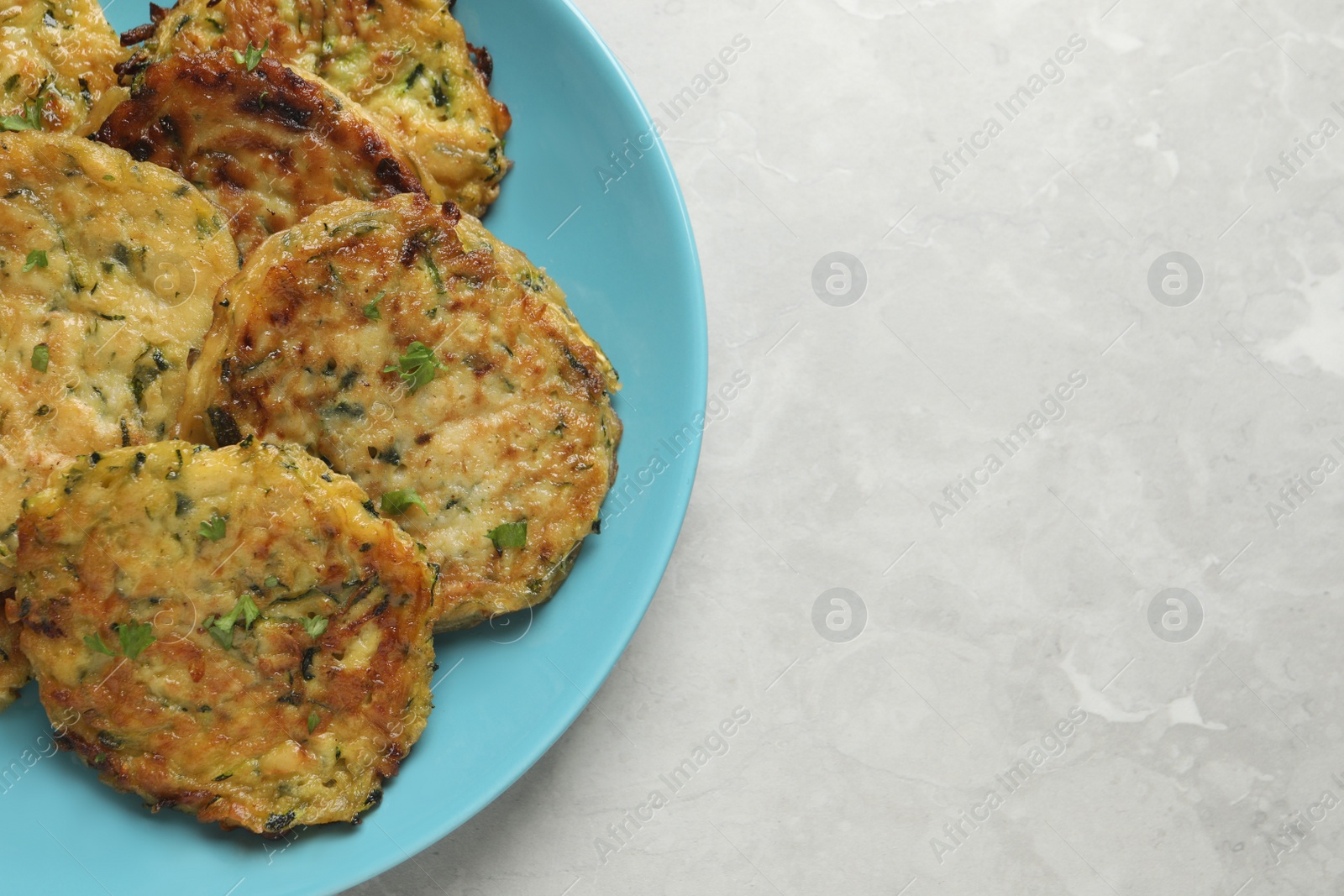 Photo of Delicious zucchini pancakes on grey table, top view. Space for text