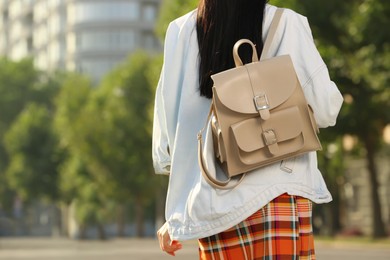 Young woman with stylish beige backpack on city street, closeup. Space for text