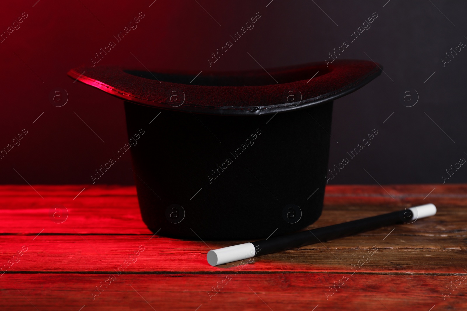 Photo of Black top hat and wand on wooden table. Magician equipment