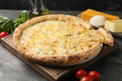 Photo of Delicious cheese pizza and ingredients on dark grey table