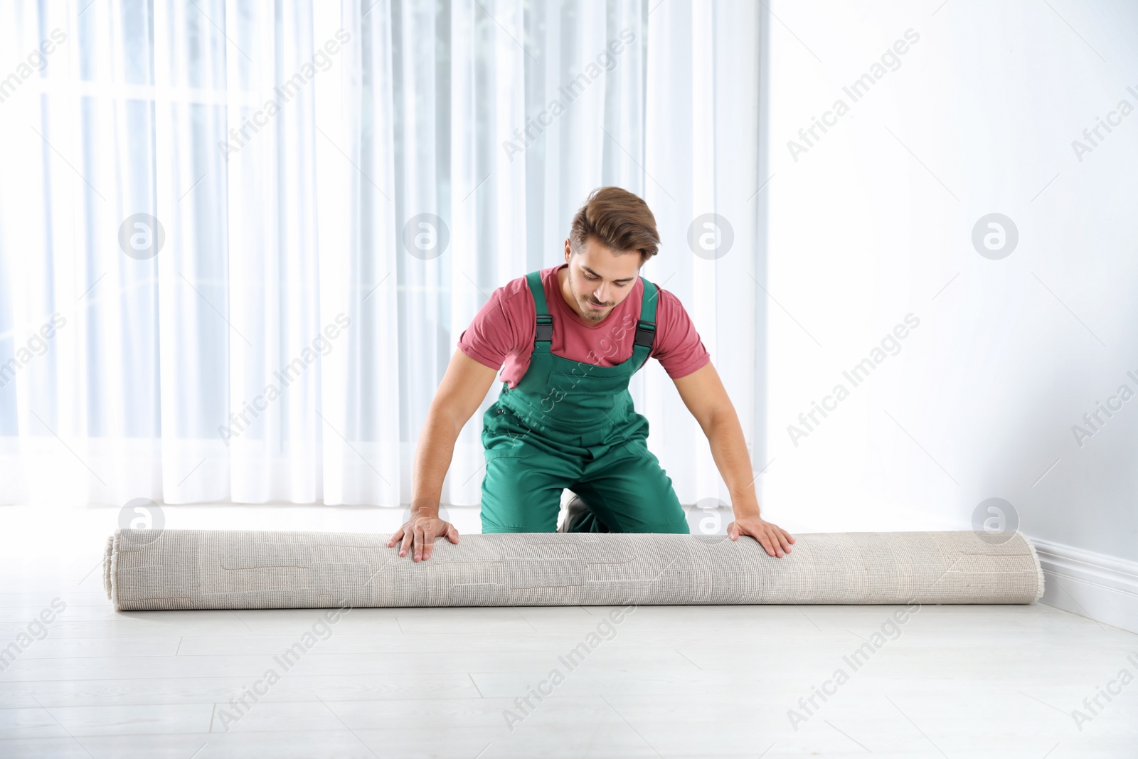 Photo of Man rolling out new carpet flooring indoors