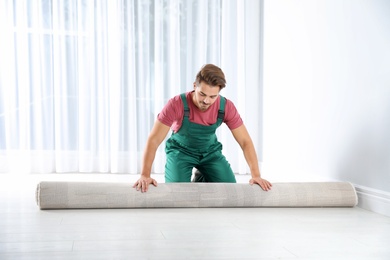 Man rolling out new carpet flooring indoors