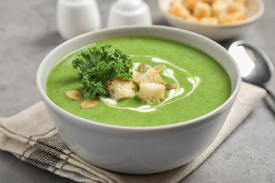 Photo of Tasty kale soup with croutons on grey table, closeup