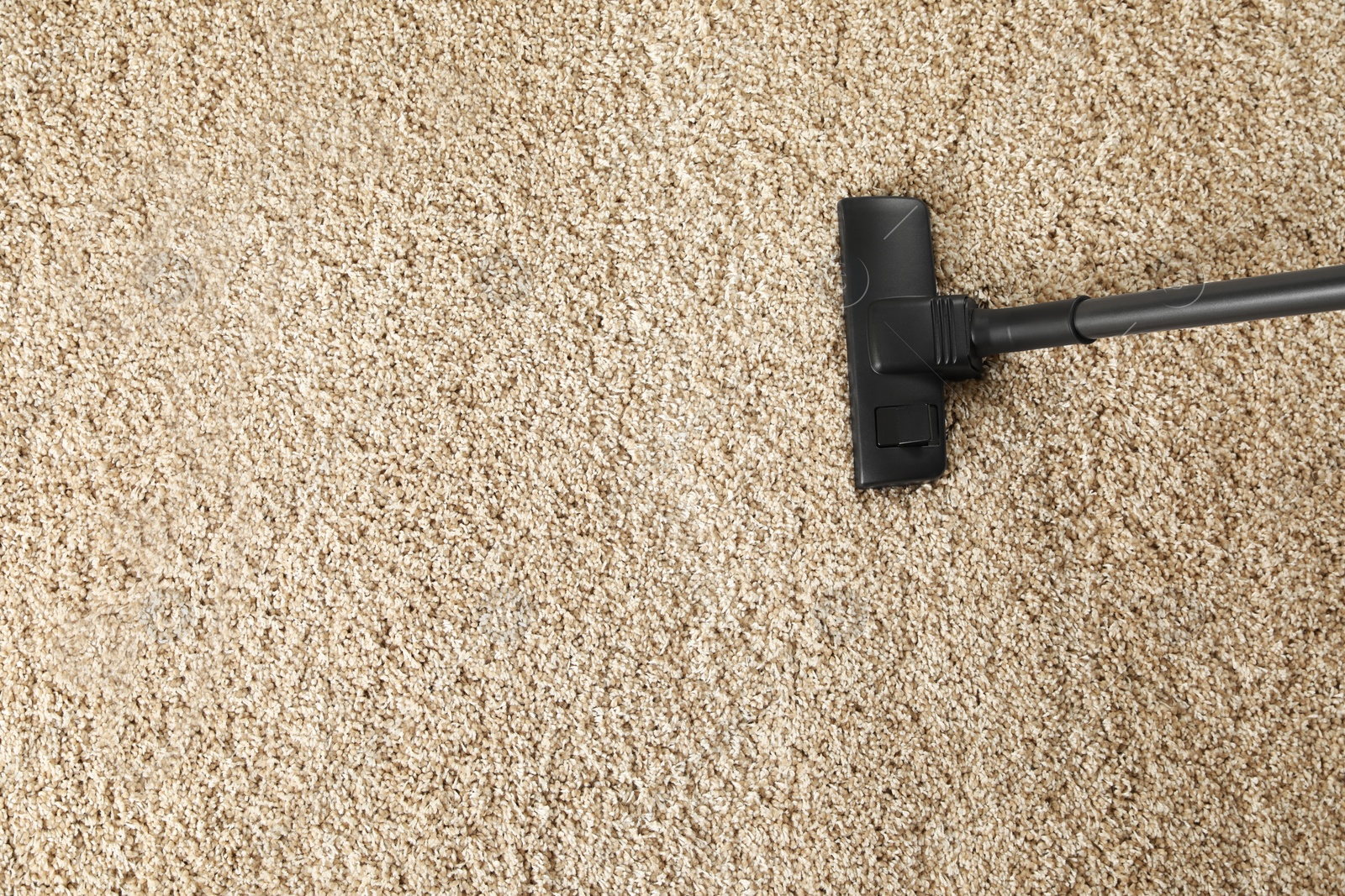 Photo of Removing dirt from beige carpet with modern vacuum cleaner, top view. Space for text