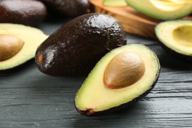 Photo of Whole and cut avocados on grey wooden table, closeup