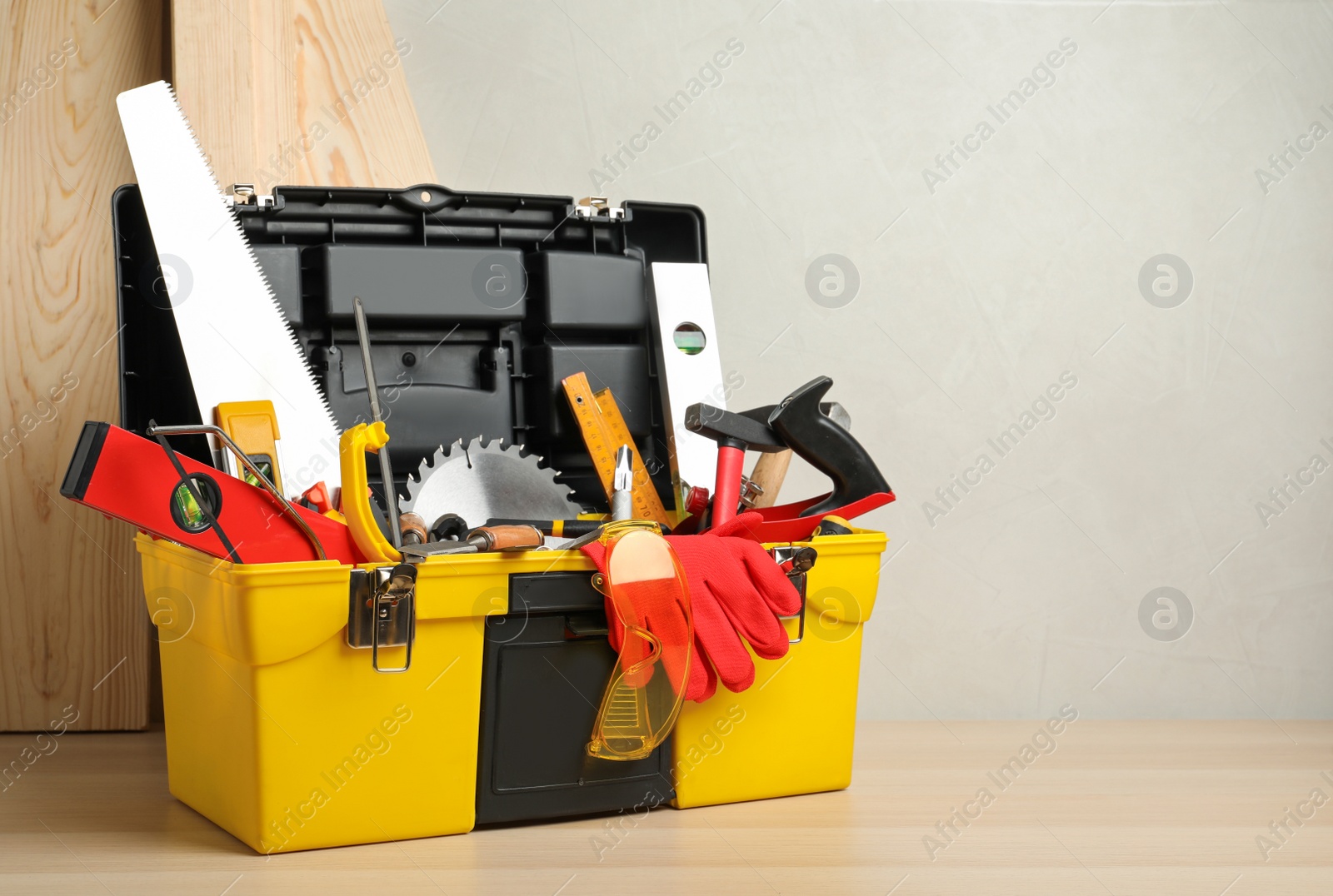 Photo of Box with different carpenter's tools on wooden table. Space for text