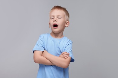 Photo of Sleepy boy yawning on light grey background. Insomnia problem