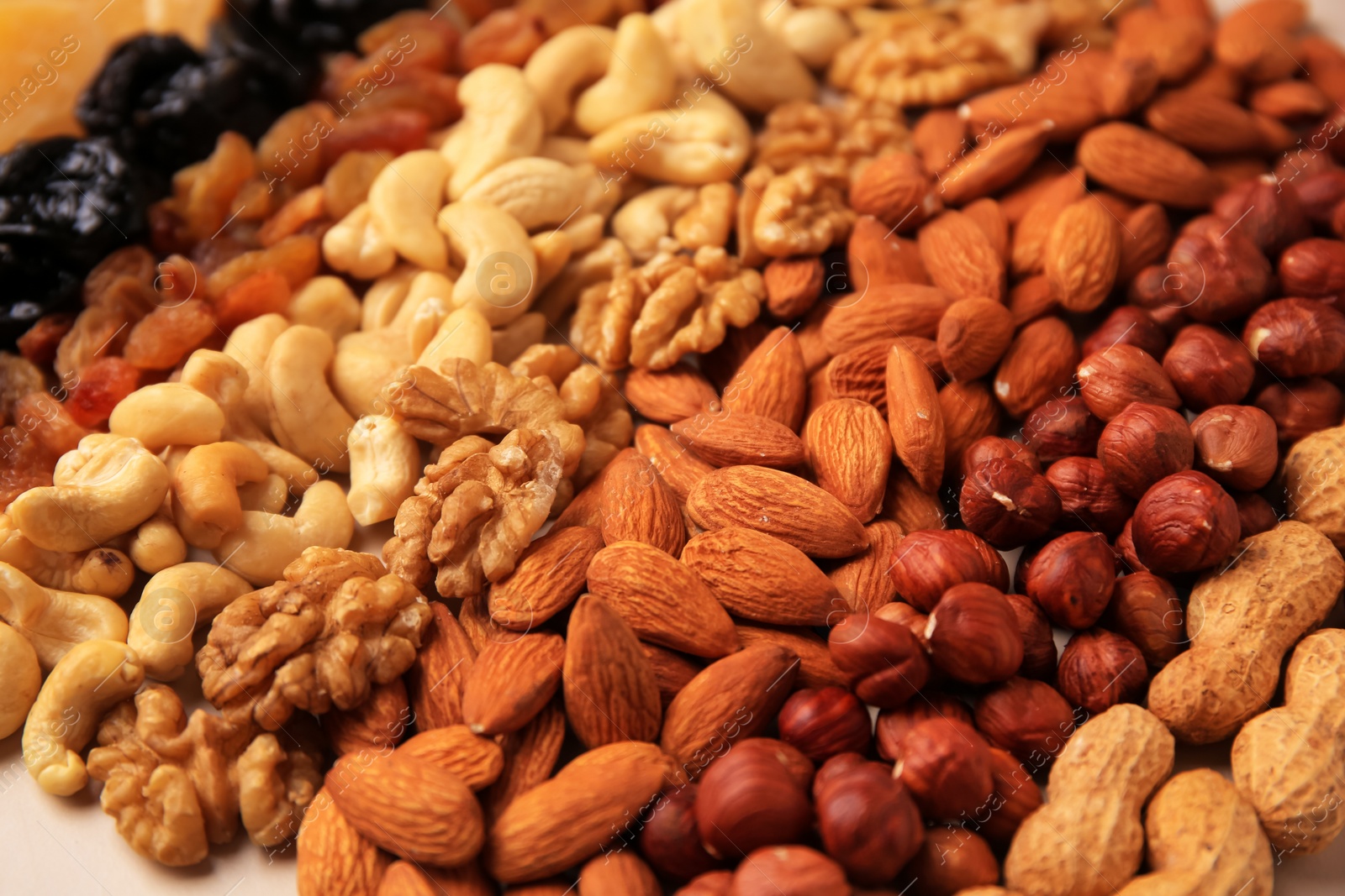 Photo of Mix of delicious dried nuts on beige background, closeup
