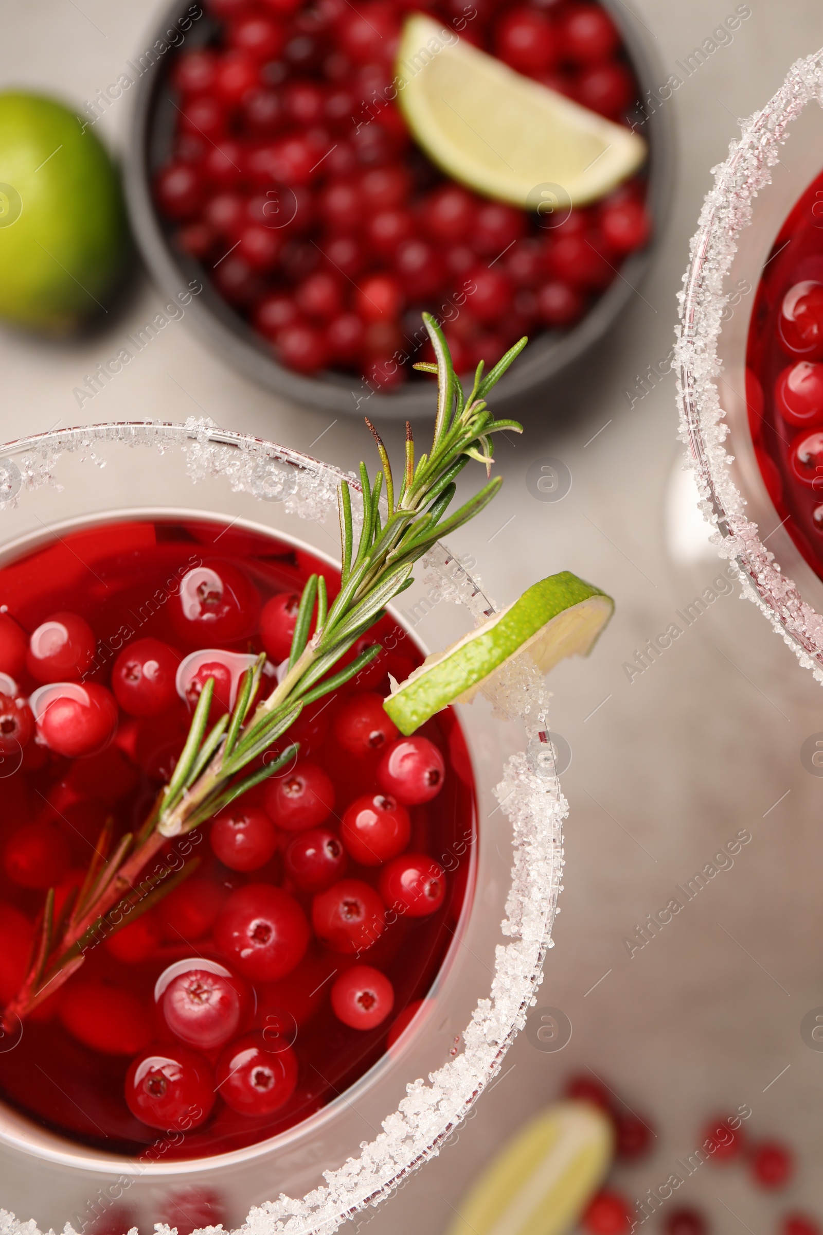 Photo of Tasty cranberry cocktail with rosemary and lime in glasses on grey table, flat lay