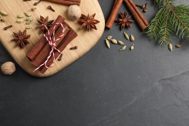 Different spices, nuts and fir branches on gray table, flat lay. Space for text