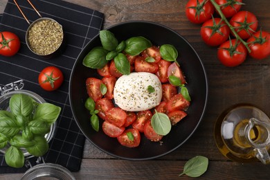 Tasty salad Caprese with mozarella, tomatoes, basil and other ingredients on wooden table, flat lay