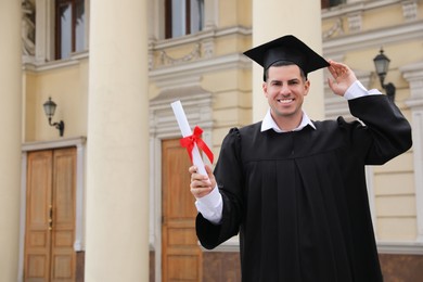 Photo of Happy student with diploma after graduation ceremony outdoors. Space for text