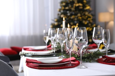 Photo of Christmas table setting with festive decor and dishware indoors