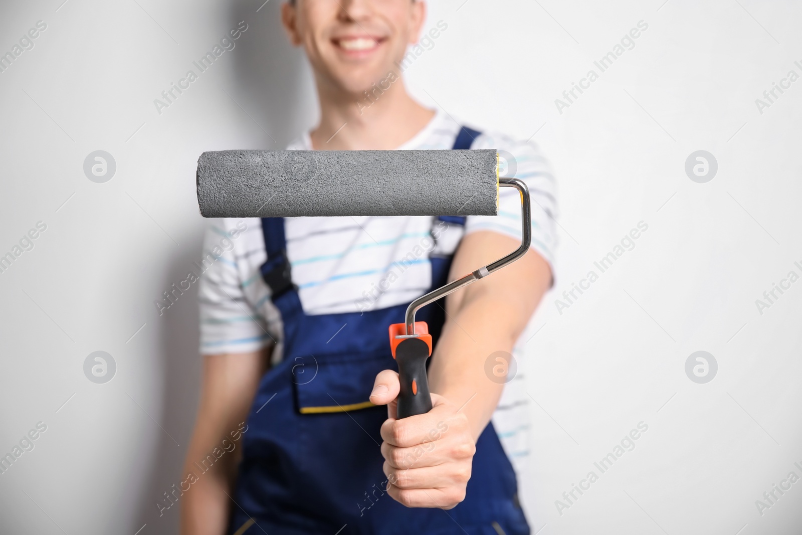 Photo of Young male decorator with paint roller on white background