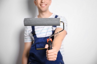 Photo of Young male decorator with paint roller on white background