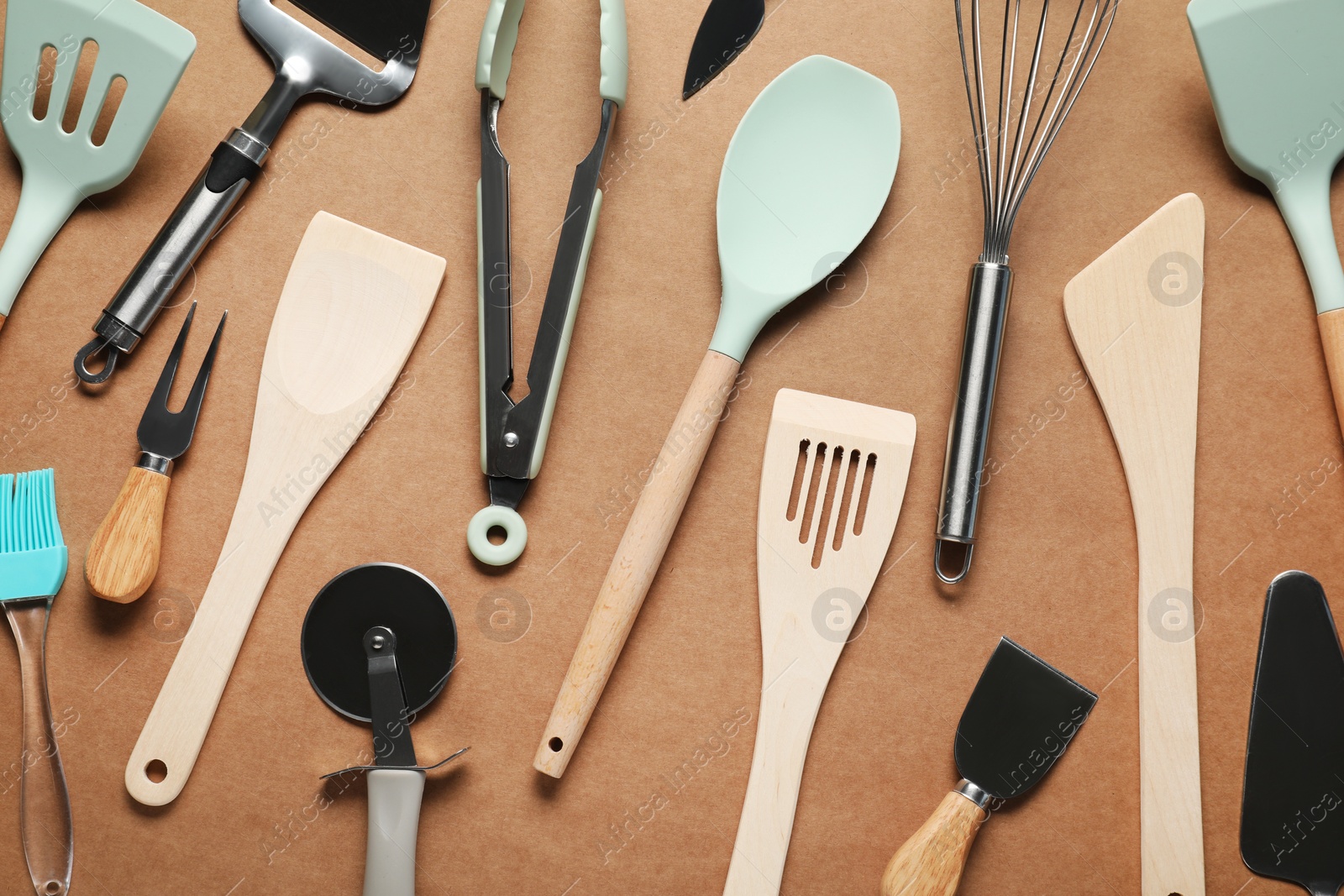 Photo of Different spatulas and other kitchen utensils on brown background, flat lay