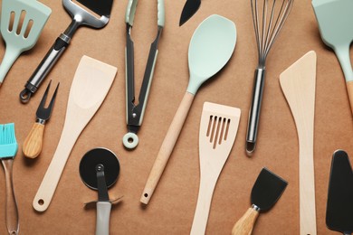 Photo of Different spatulas and other kitchen utensils on brown background, flat lay