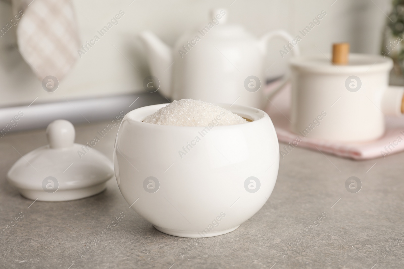 Photo of Ceramic bowl with white sugar on grey table