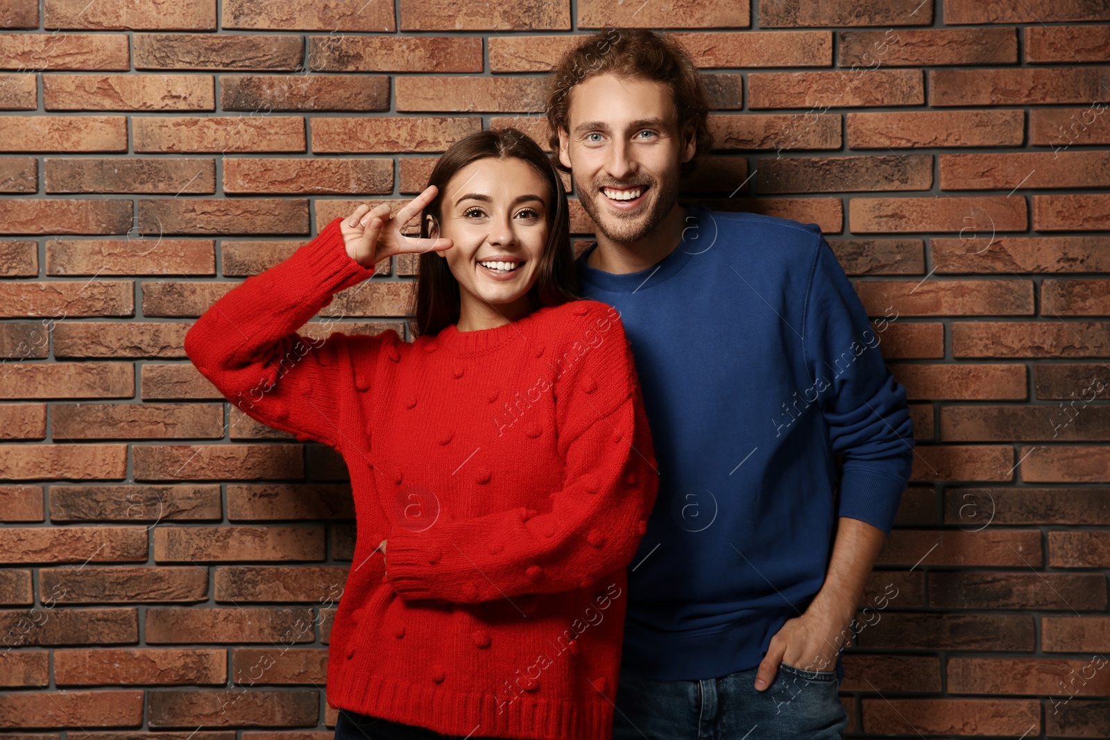 Photo of Young couple in warm sweaters near brick wall