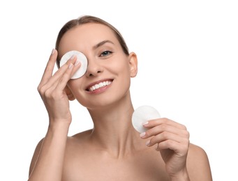 Smiling woman removing makeup with cotton pads on white background