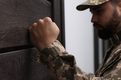 Photo of Military commissariat representative knocking on wooden door, selective focus