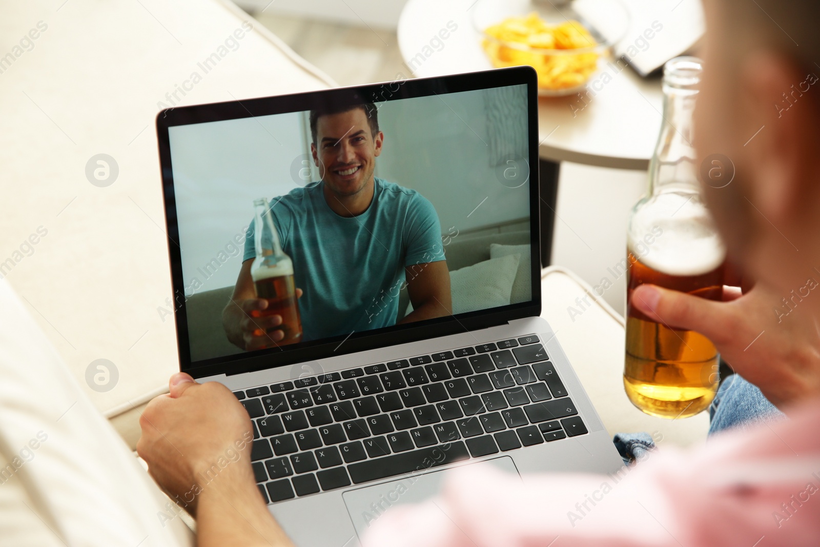 Photo of Friends drinking beer while communicating through online video conference at home. Social distancing during coronavirus pandemic