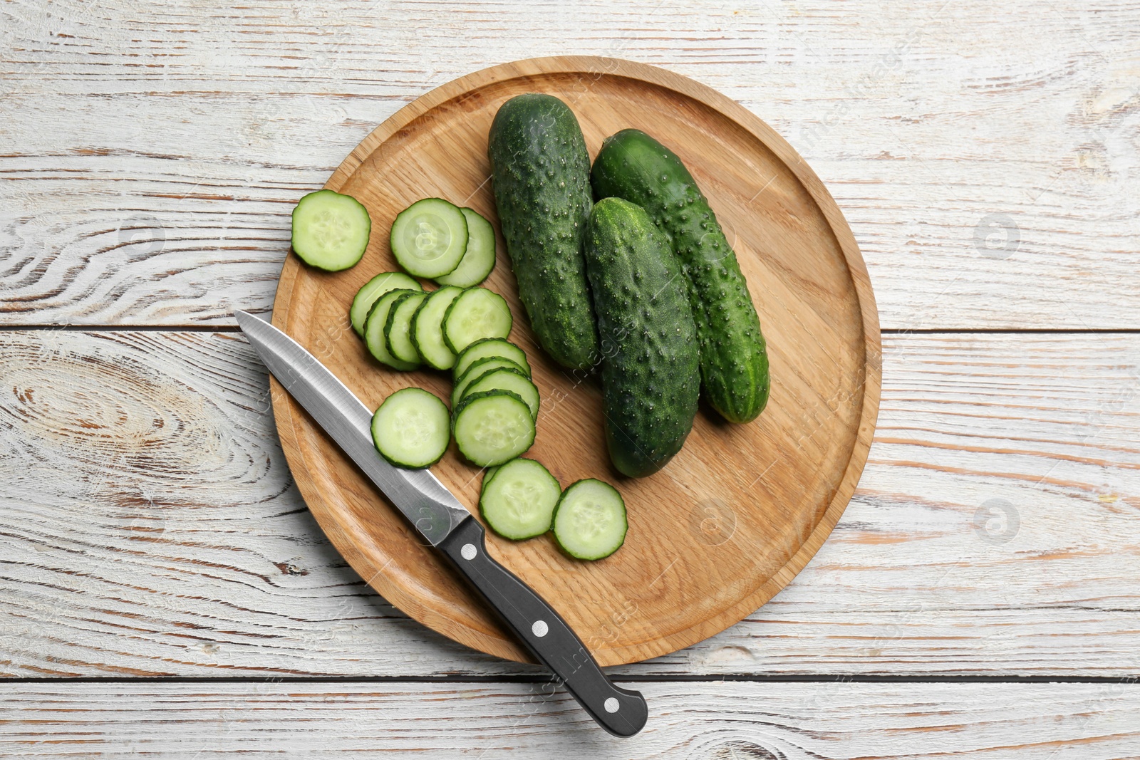 Photo of Whole and cut fresh ripe cucumbers on white wooden table, flat lay