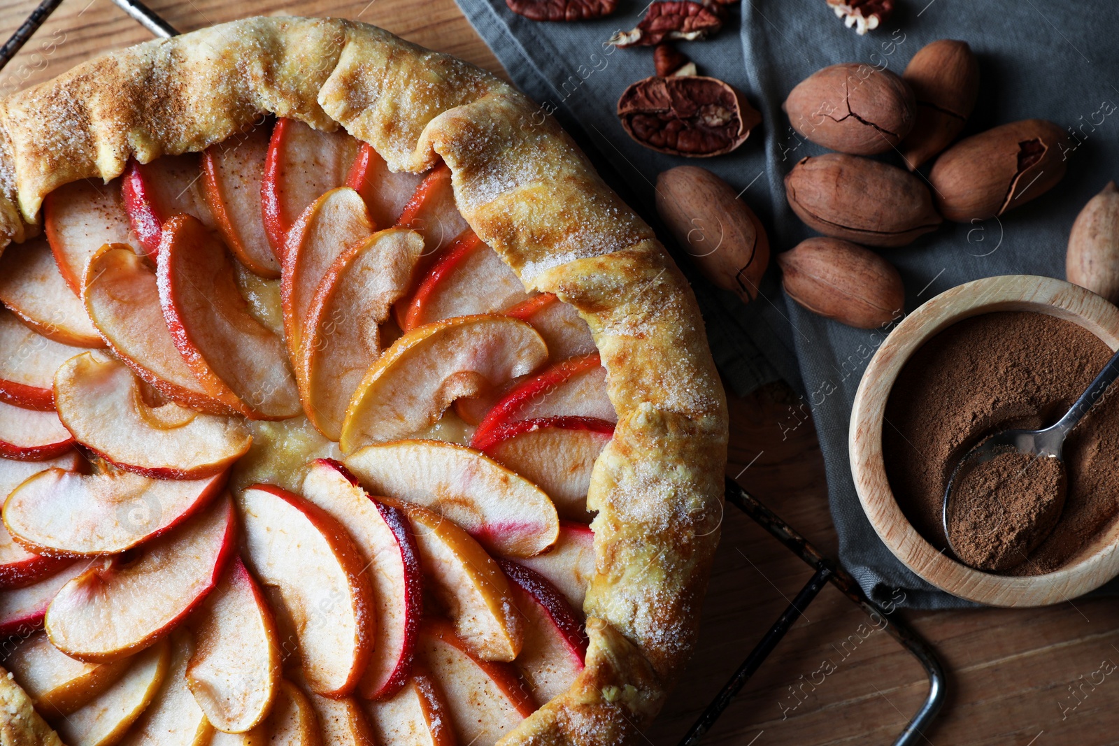 Photo of Delicious apple galette, cinnamon and pecans on wooden table, flat lay