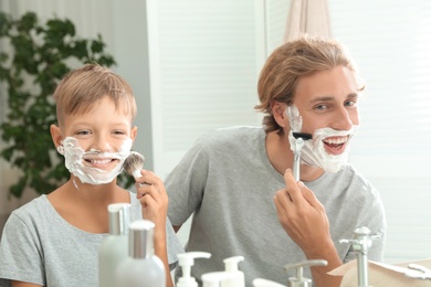 Photo of Father and son shaving together in bathroom