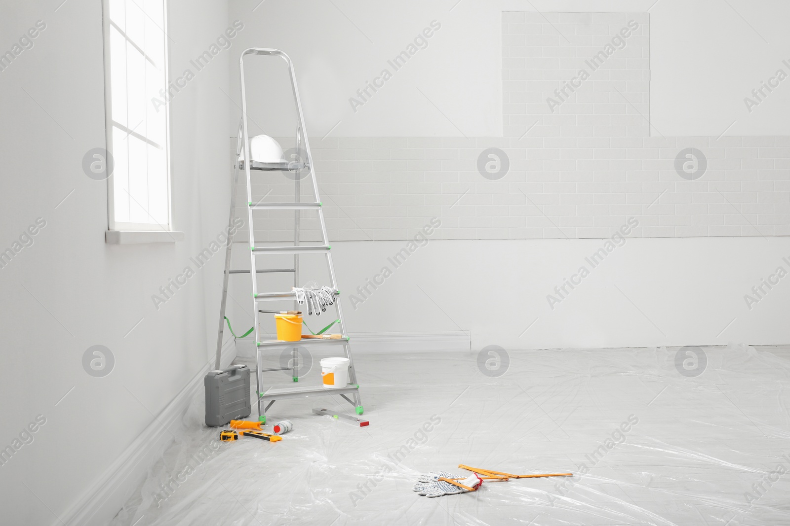 Photo of Stepladder and different tools near wall in room, space for text. Interior renovation