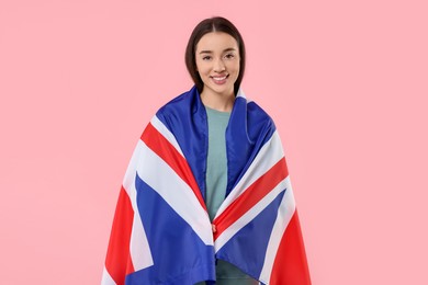 Young woman with flag of United Kingdom on pink background