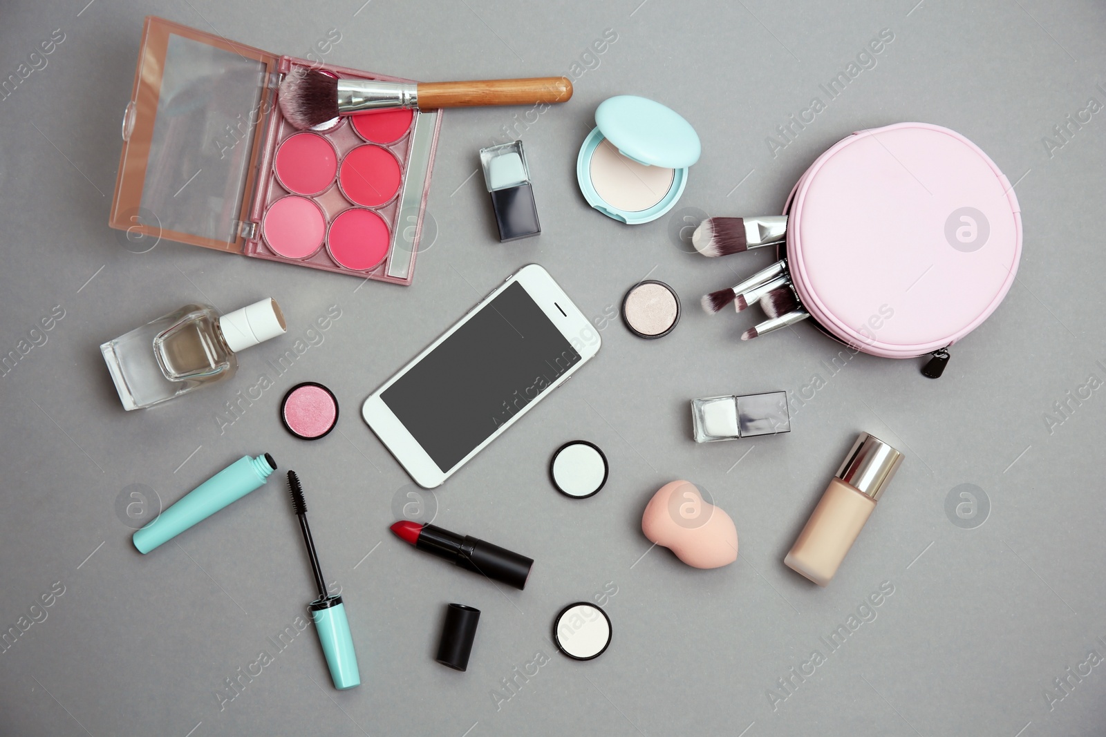 Photo of Flat lay composition with smartphone and makeup products for woman on grey background