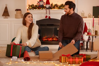 Photo of Happy couple decorating Christmas gifts at home