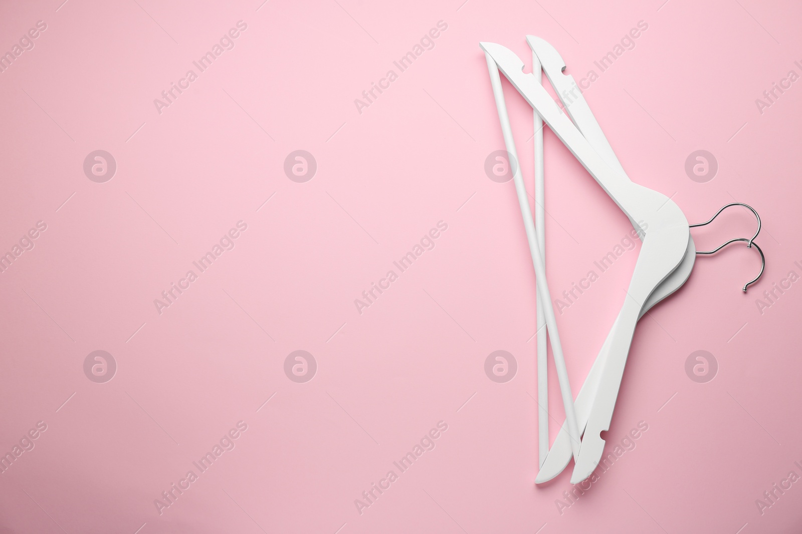 Photo of White hangers on pink background, top view. Space for text