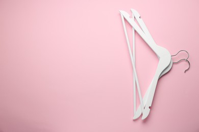 Photo of White hangers on pink background, top view. Space for text