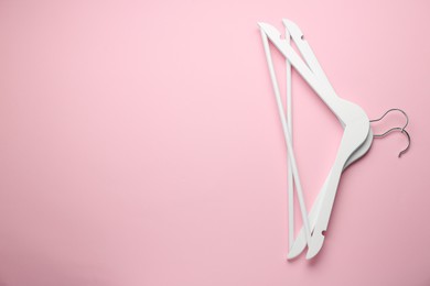 White hangers on pink background, top view. Space for text