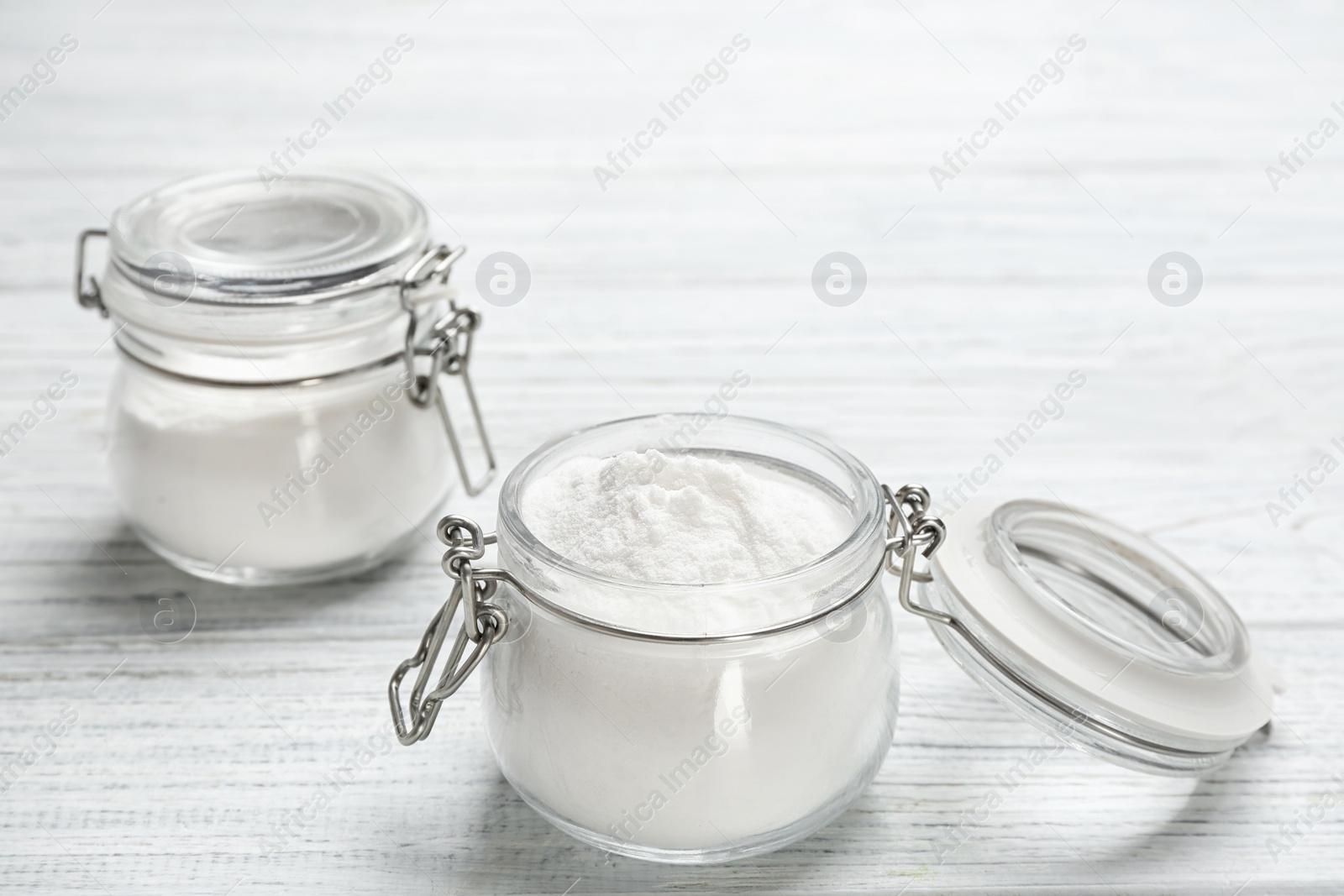 Photo of Jars with baking soda on white wooden background