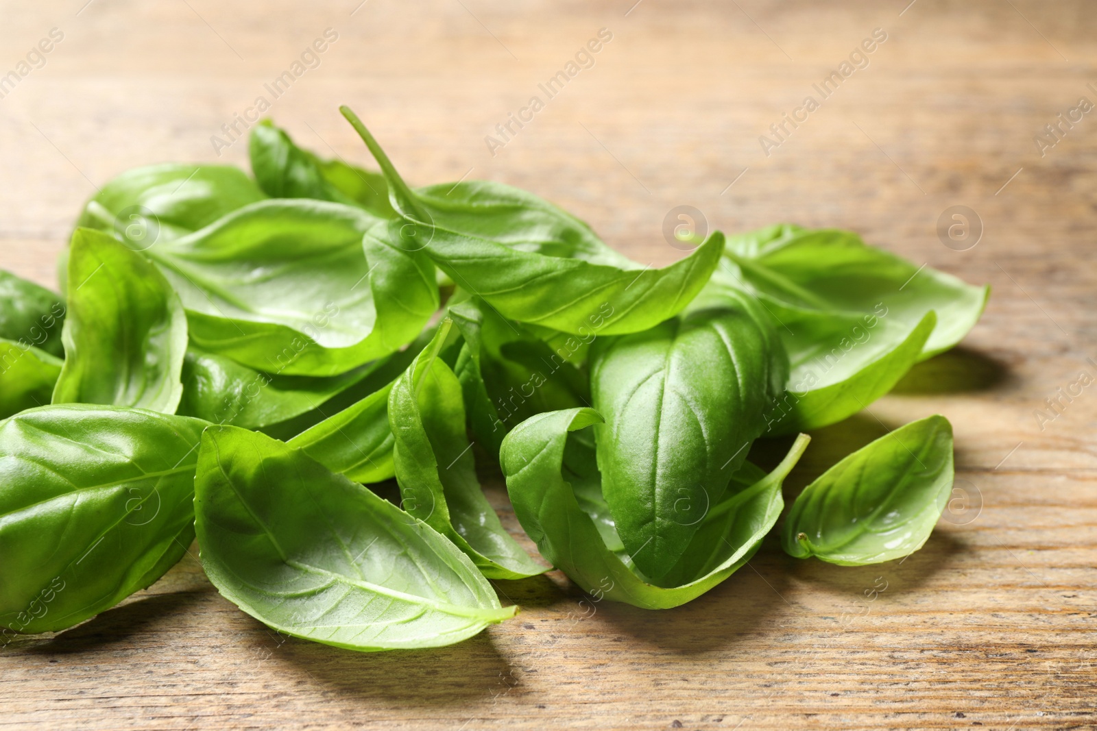 Photo of Fresh basil leaves on wooden table, closeup