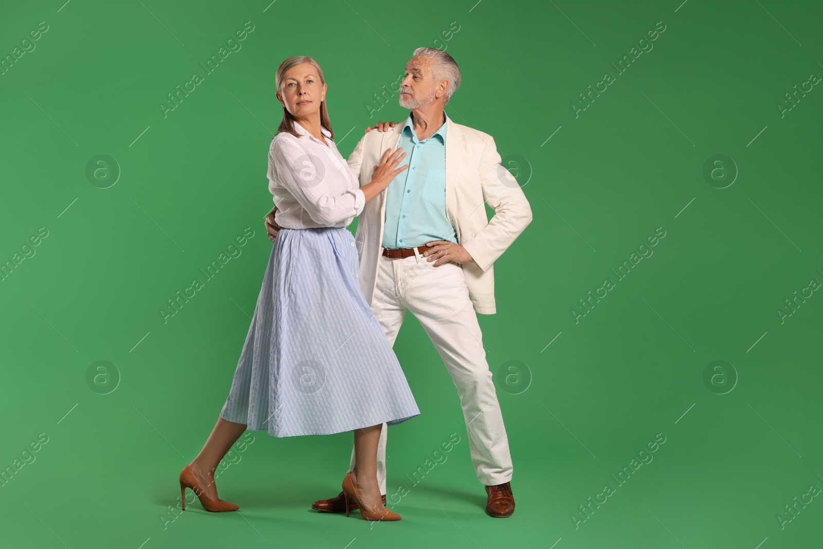 Photo of Senior couple dancing together on green background