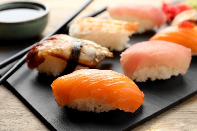 Serving board with delicious nigiri sushi and soy sauce on wooden table, closeup