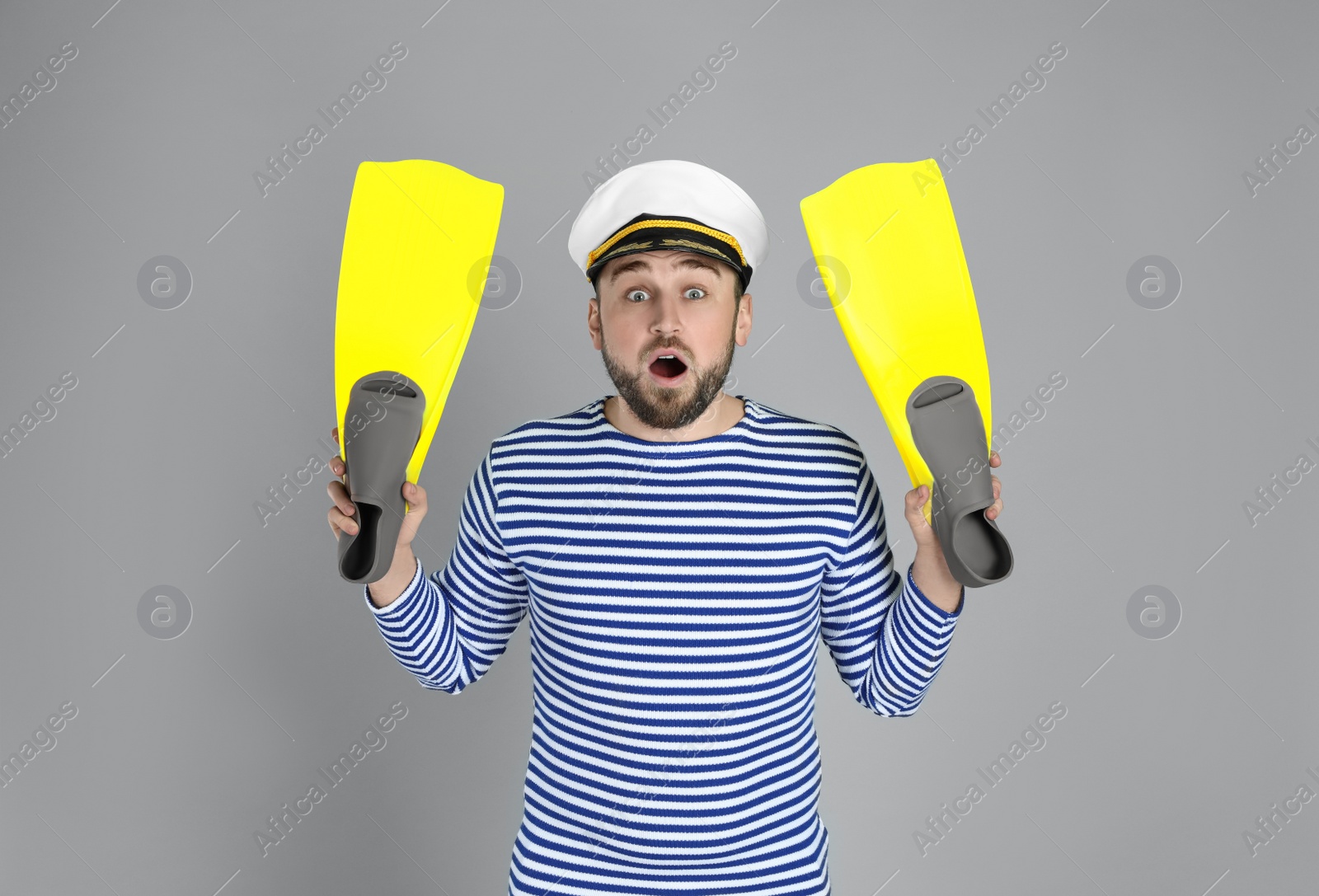 Photo of Emotional sailor with swim fins on light grey background