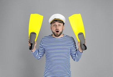 Emotional sailor with swim fins on light grey background