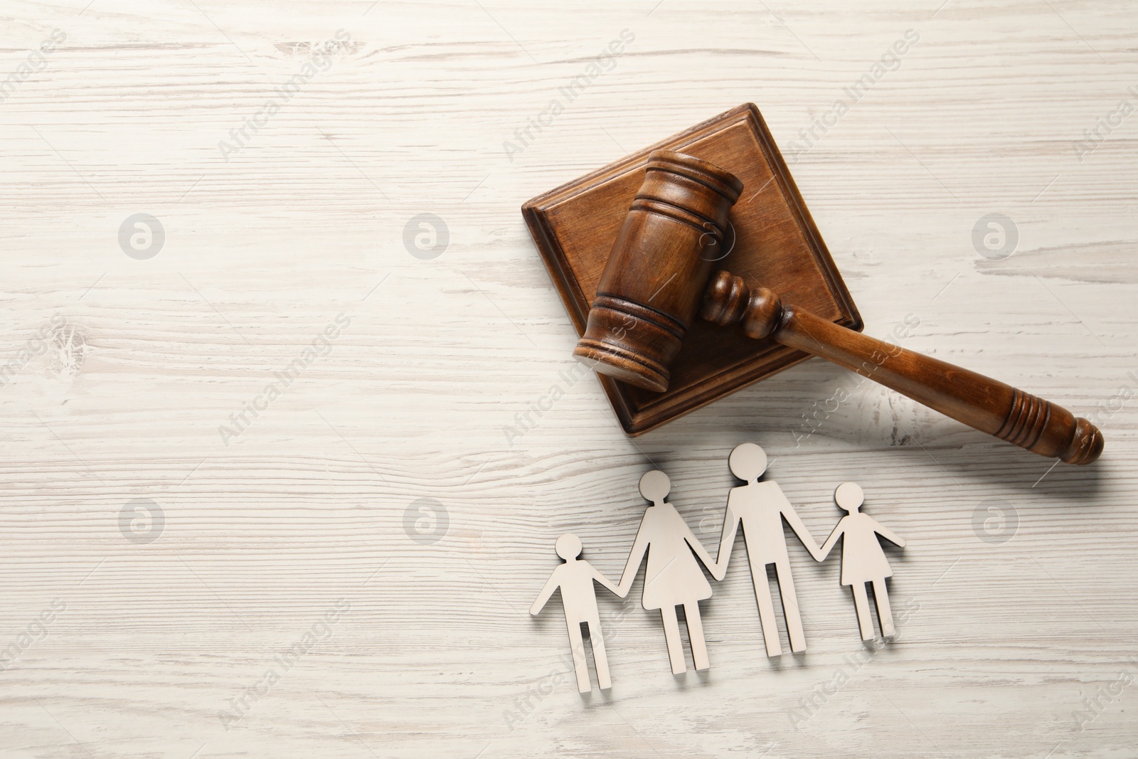 Photo of Law concept. Gavel and figures of parents with children on white wooden table, top view. Space for text