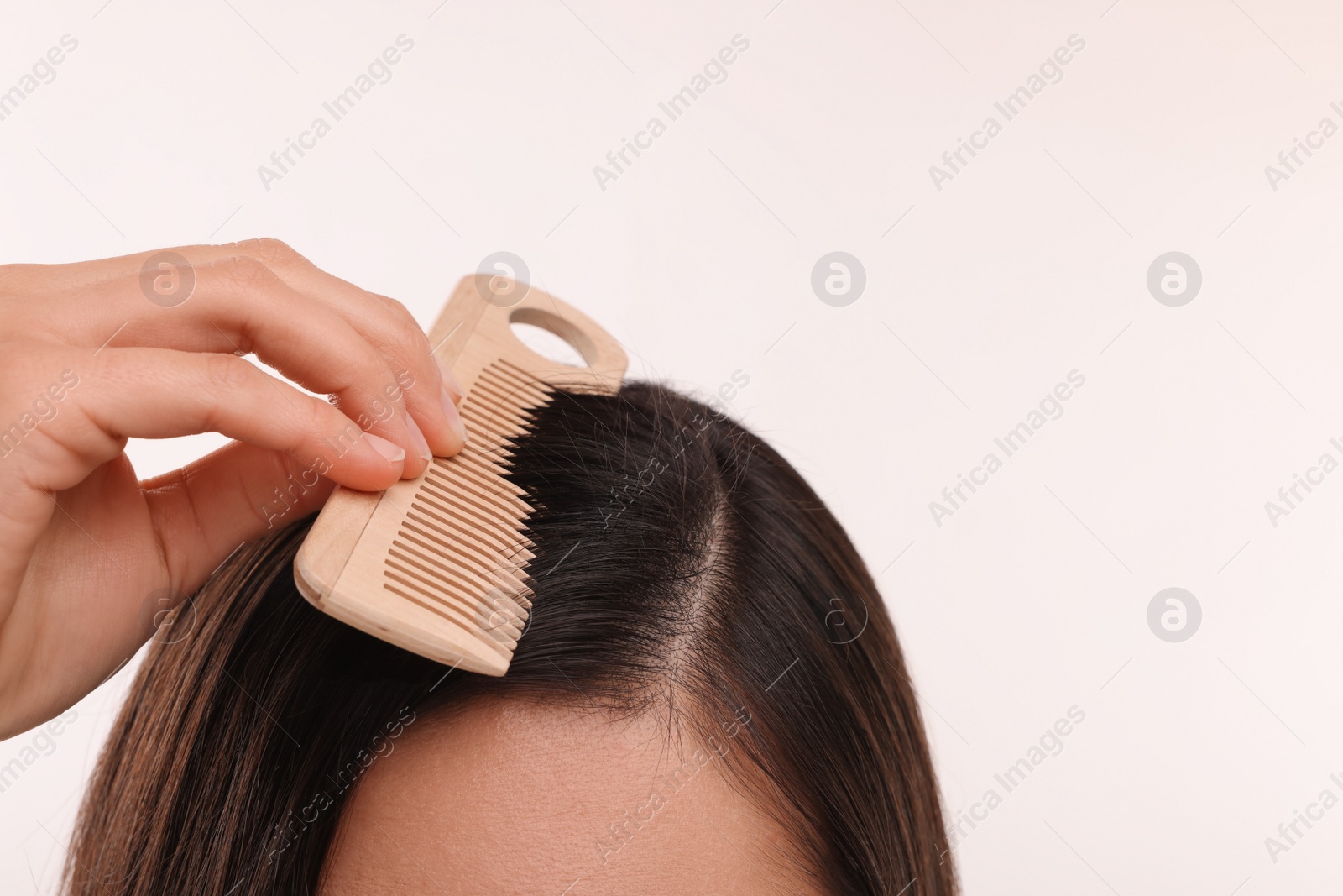 Photo of Woman with comb examining her hair and scalp on white background, closeup. Space for text