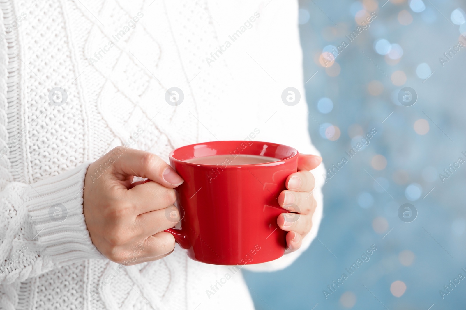 Photo of Young woman with delicious hot cocoa drink on blurred background, closeup